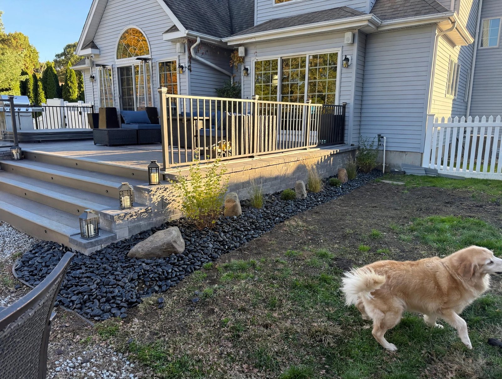 Hot tub built into a custom deck with black railing and stone skirting in Suffield, Connecticut